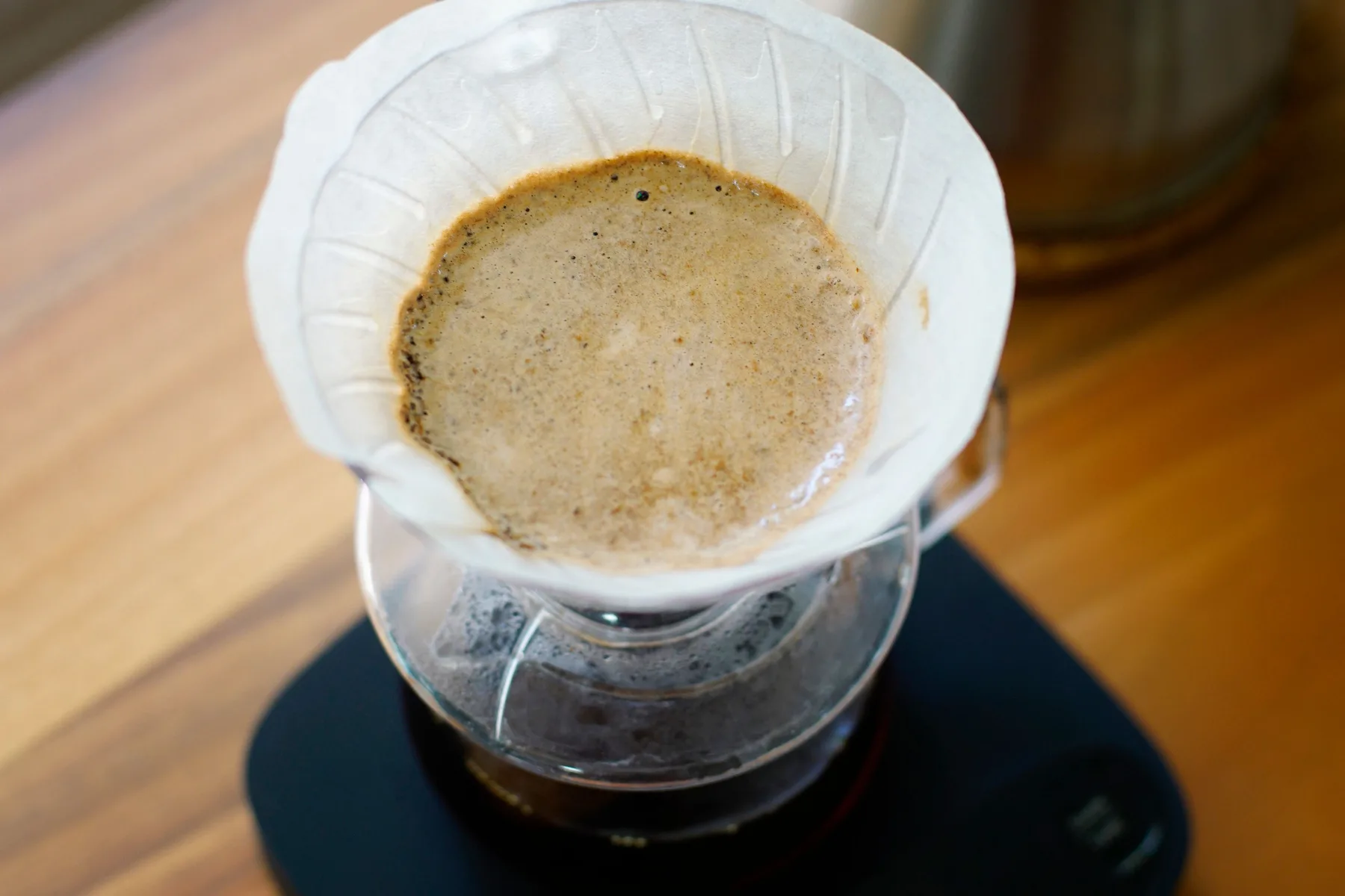 A pour-over brewer resting on a digital coffee scale