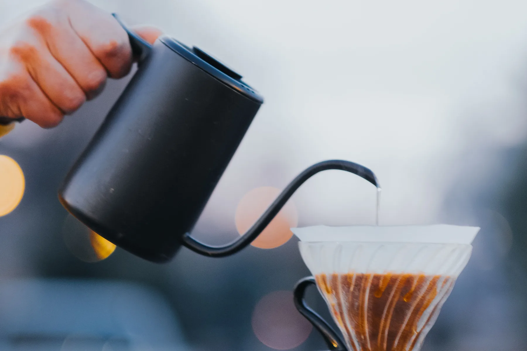 A kettle pouring water into a coffee dripper